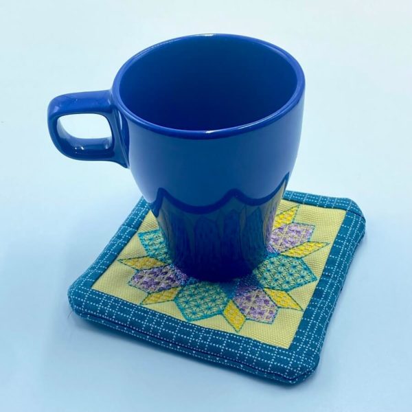 a blue cup sitting on top of a coaster in Embroidery Design